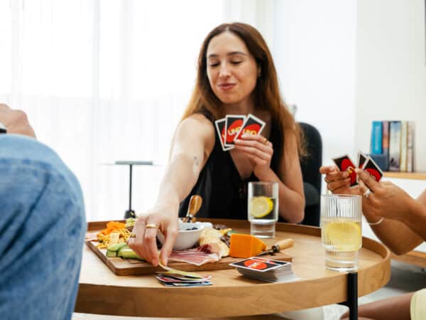 A pack of UNO cards has broken out within the first home buyer and their friends. The charcuterie board is in frame with a neutral beige rug under the coffee table. This first home design is a perfect first home for entertaining, built by Step 1 Homes.