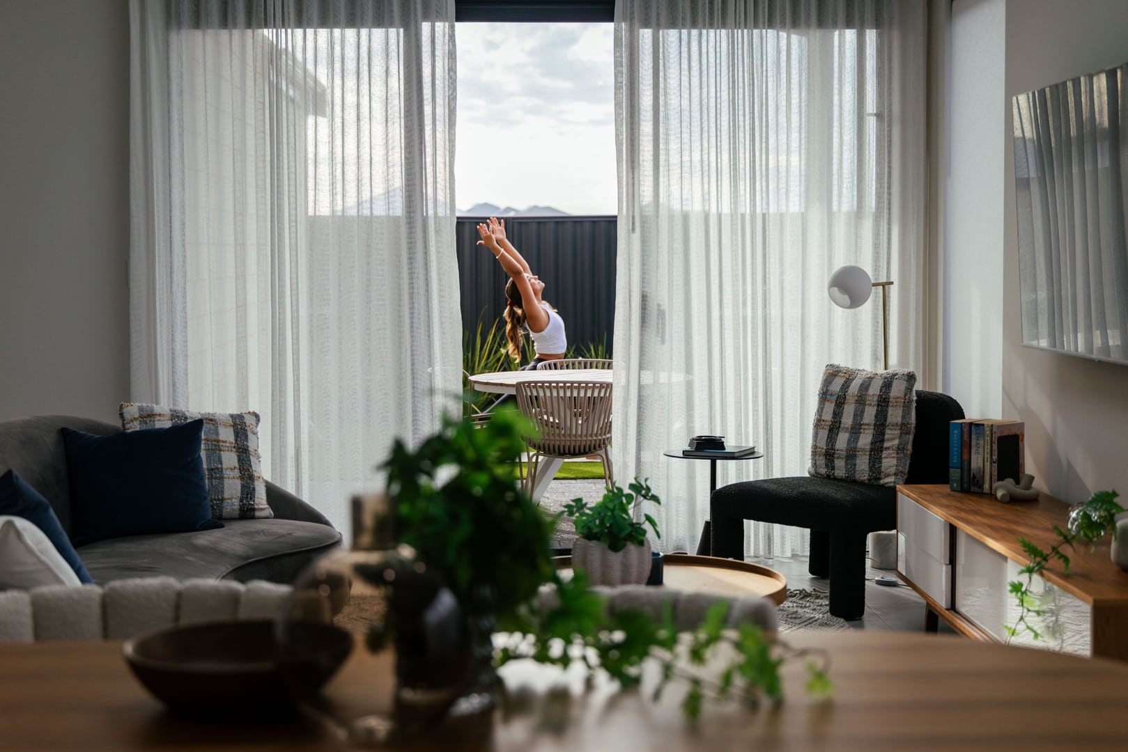 First home buyer created a space for wellness in her new first home, suited to her lifestyle. The view from the dining and living room shows her standing in 'mountain' yoga pose on her yoga mat, on the grass in the backyard. Built by Step 1 Homes, this home design is spacious, functional and has room for hobbies - the perfect home design for the modern homeowner.